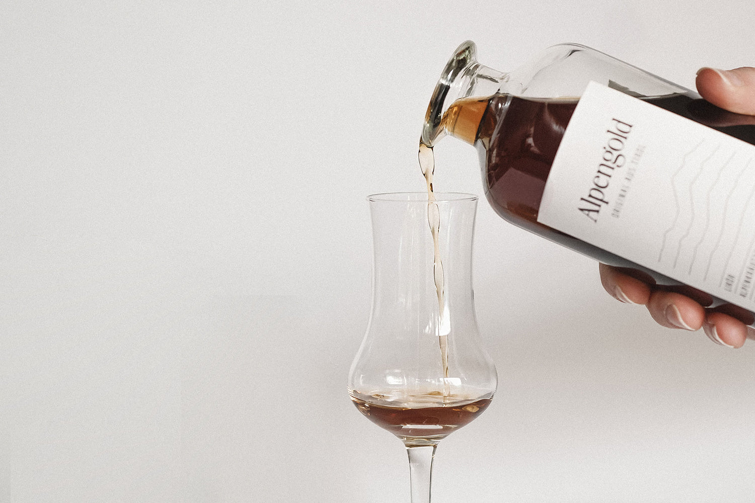 Alpengold Heuschnaps wird aus der Flasche in ein Glas eingeschenkt